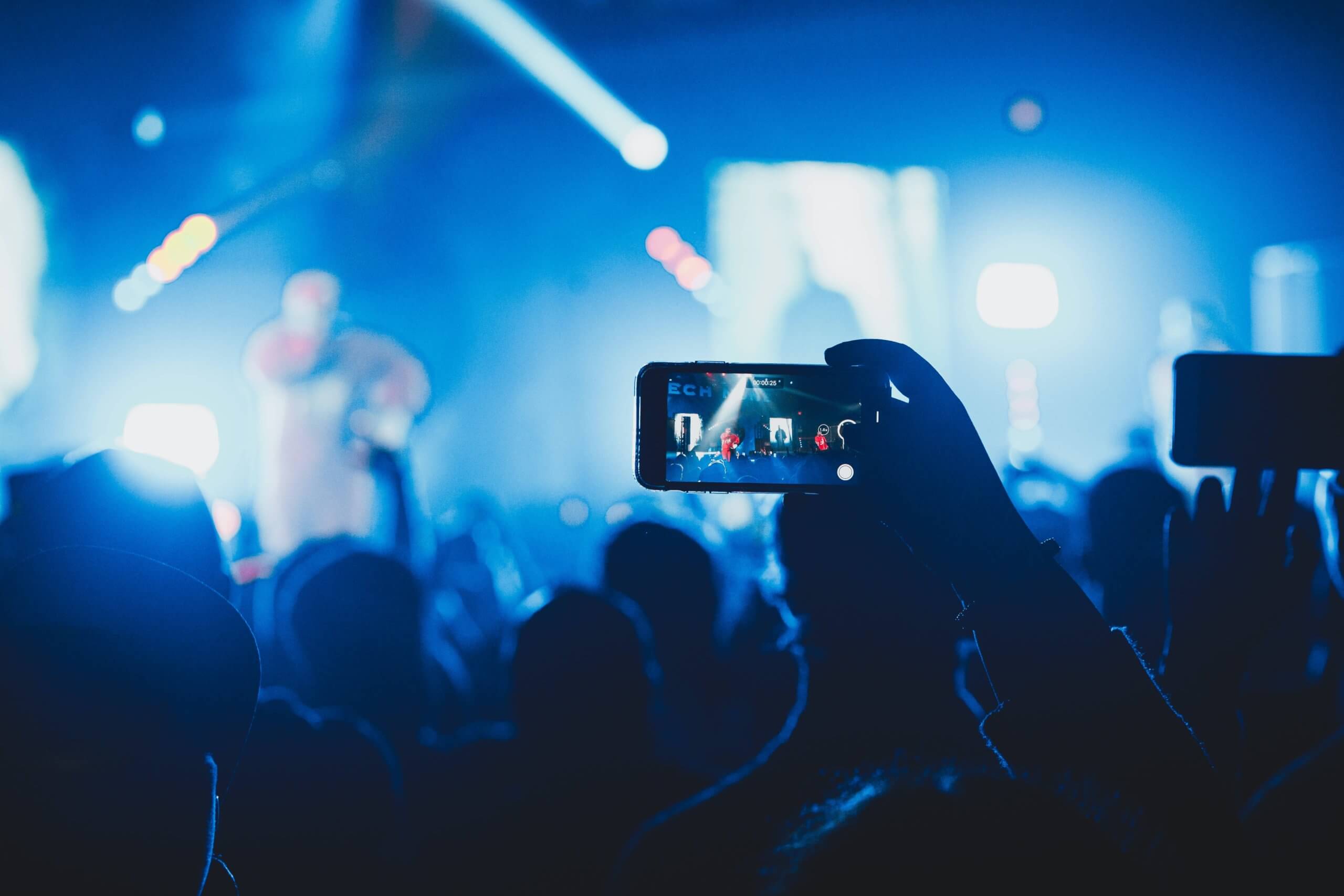 someone holding phone at music concert live streaming